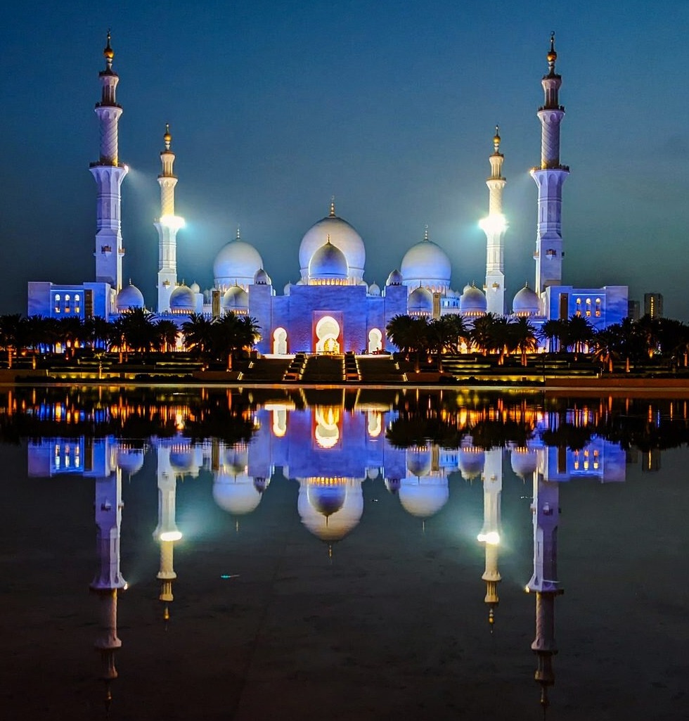 Sheikh Zayed Grand Mosque reflected in still water at night.