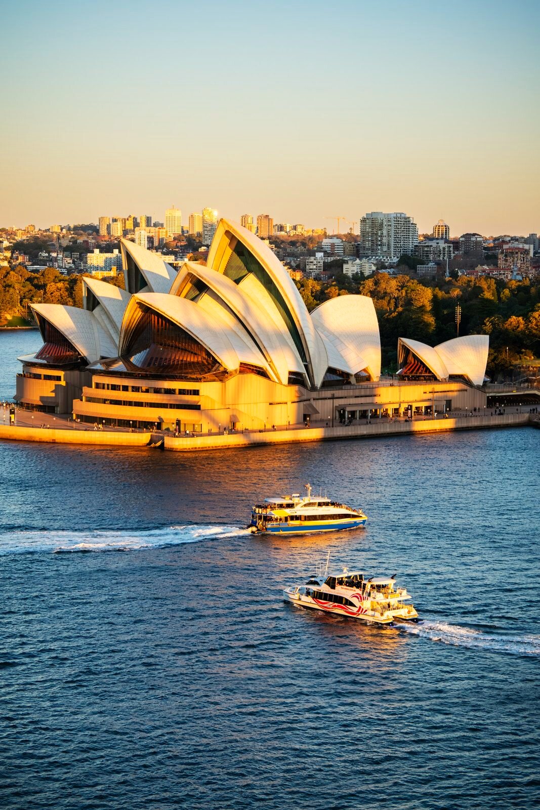 Sydney Opera House with ferries crossing the harbor.