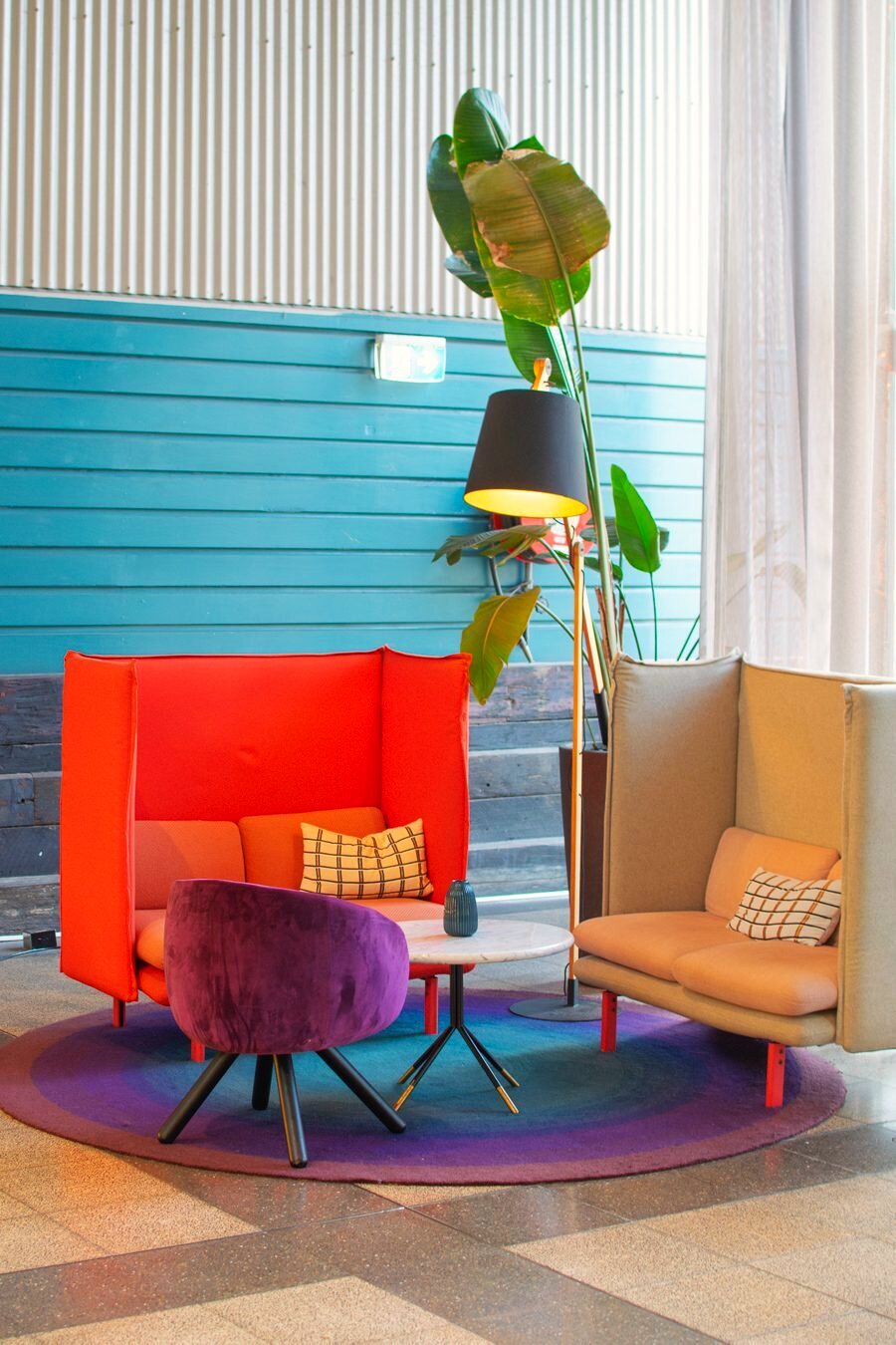 Colorful hotel lobby lounge with high-backed sofas and a potted plant.