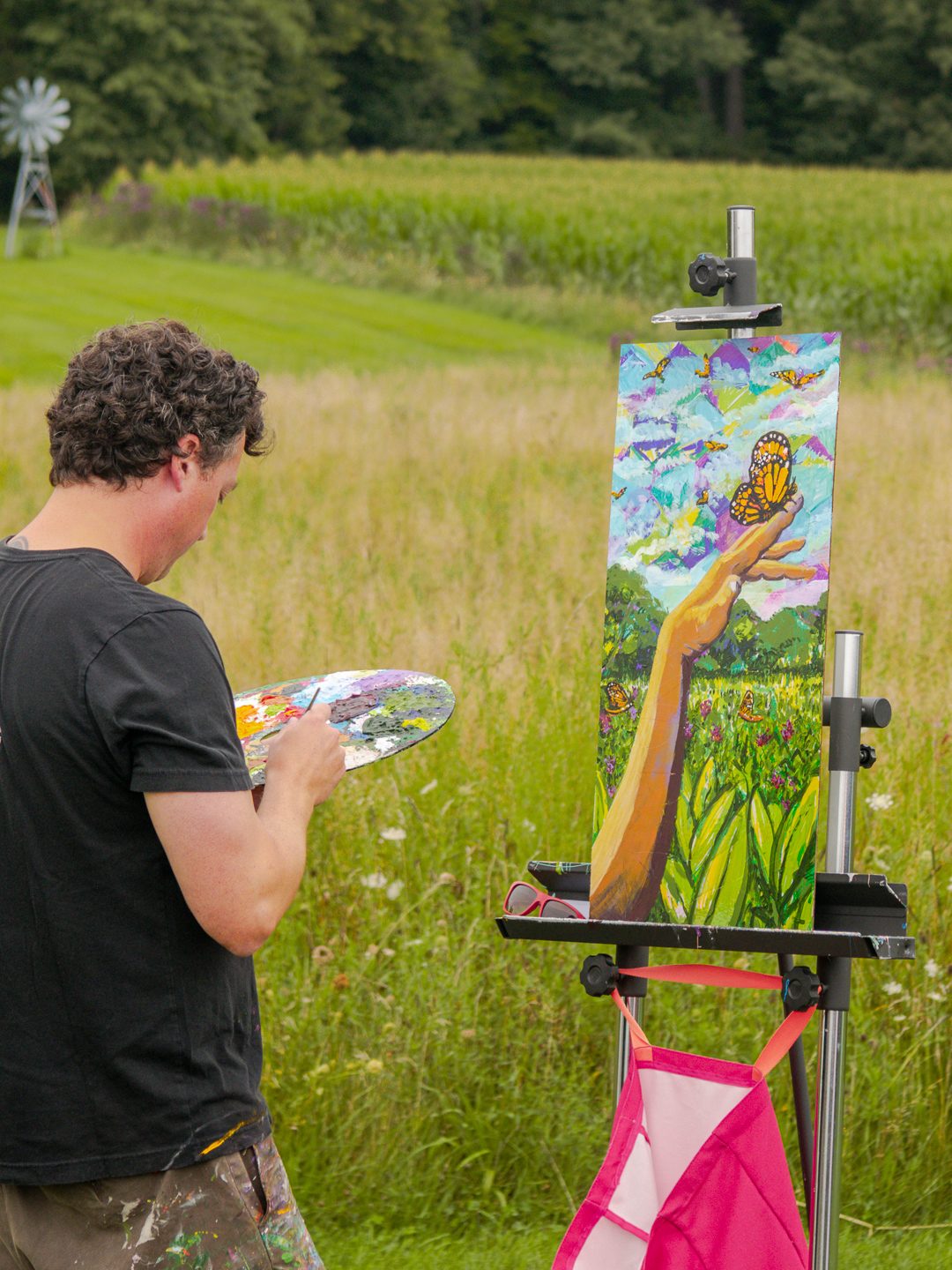 An artist painting at an easel in a meadow during the Butterfly Gala.