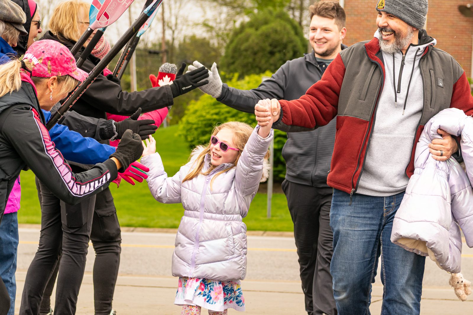 A young girl in a white coat high-fiving a line of cheering volunteers at the Hope Walk.